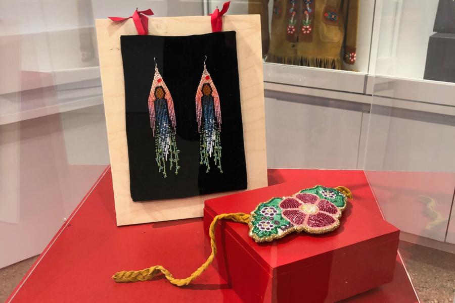 A pair of beaded earrings created by Bronwyn Butterfield titled, She Is The Land. And a Beaded Applique Belt created by Niamh Dooley as part of the Adornment exhibit. 
