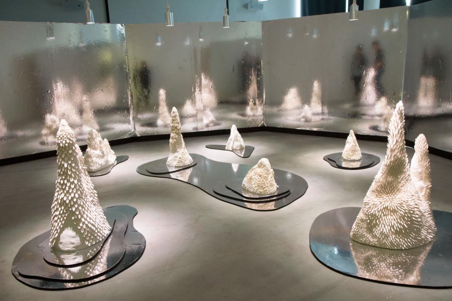 A display of E. Shumkas student work on display featuring various sizes of cone shaped pieces sitting atop metallic silver bases.
