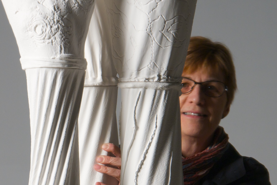 Grace Nickel standing behind a tall ceramic sculpture