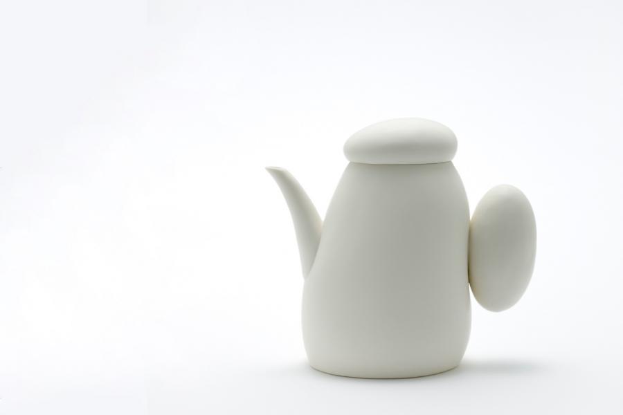 A white ceramic tea-pot sits in a white backdrop