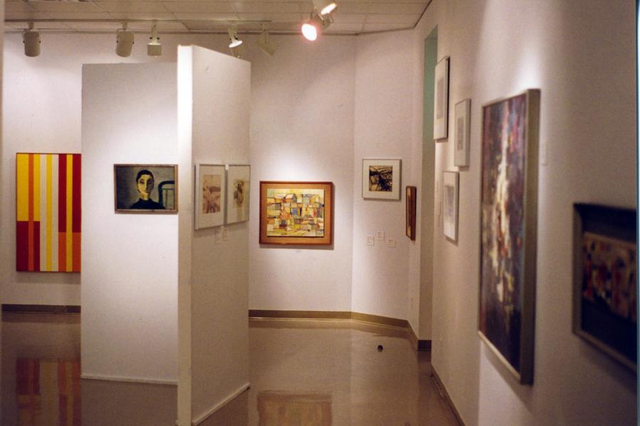 Over all image of the exhibition "Modernism at Play" featuring a white wall with numerous colourful painting varying in size.
