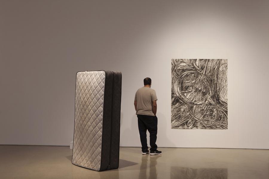 A man stands in front of a charcoal drawing.