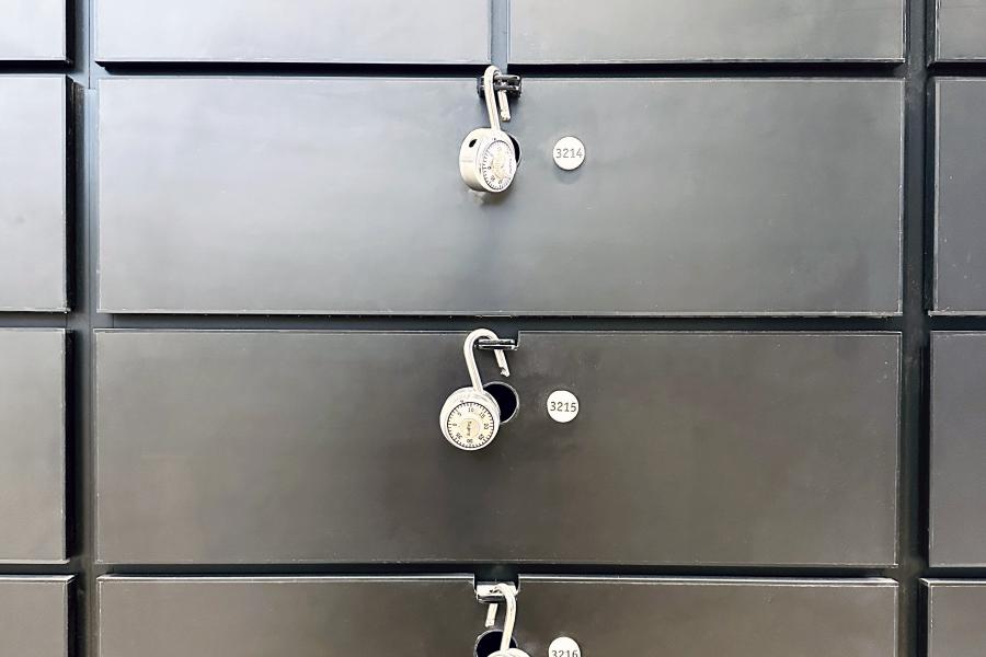 Four black, stacked flat-folder lockers with open combination locks.