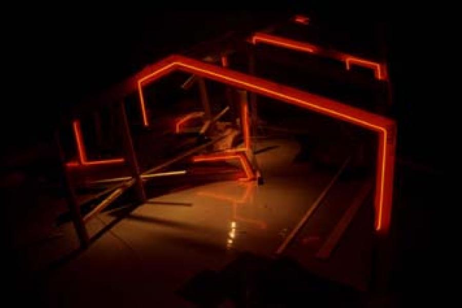 A single small neon house floating in darkness, casting a soft red glow onto the surrounding surface. The minimalist composition highlights the house as a symbol of memory, transformation, and disappearance.  