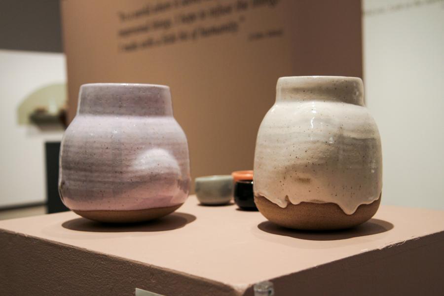 Close-up of two rounded ceramic jars, one in pastel purple and the other in off-white with a speckled glaze.