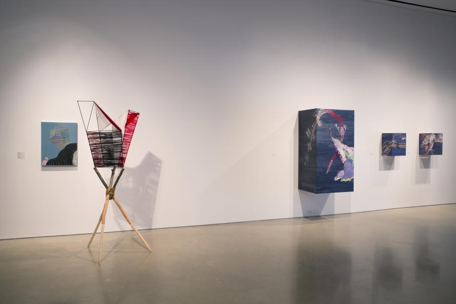 A detail of wall-mounted and freestanding artworks, including a vibrant geometric sculpture and colourful abstract paintings.