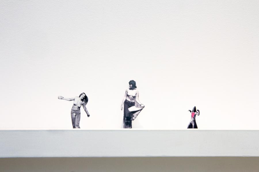 Three small black-and-white figurative cutouts displayed on a white ledge.