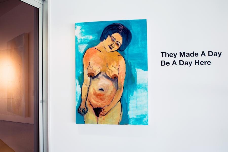 A vibrant painting of a semi-nude woman with an expressive pose on a white wall, next to text reading, "They Made A Day Be A Day Here."