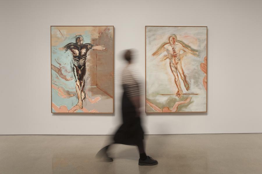 A blurred visitor walking past two dynamic paintings by Sheila Butler, capturing the fluid energy and emotive gestures of the works.