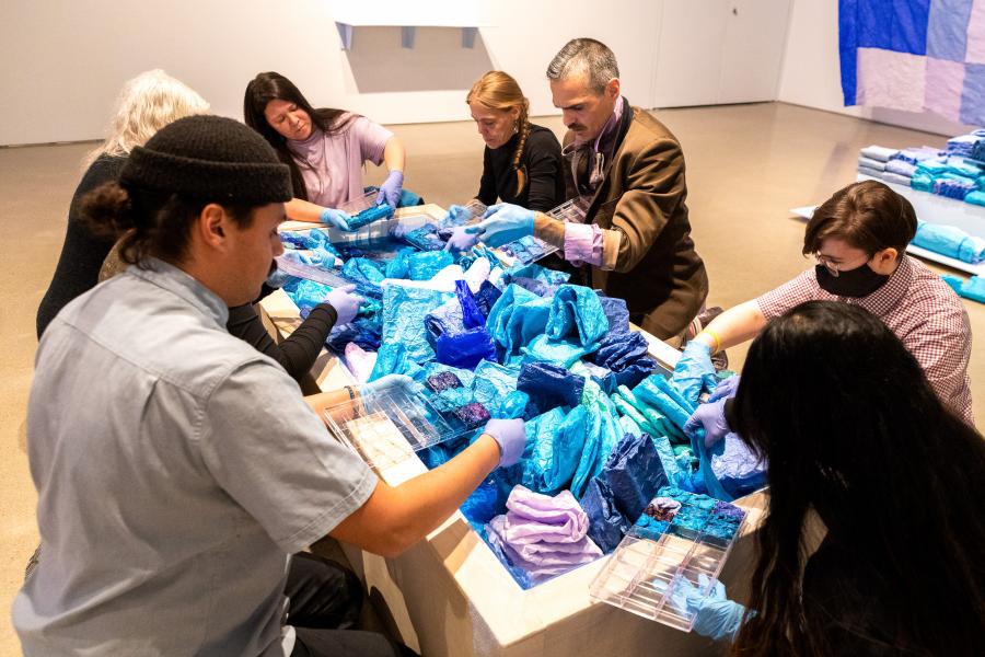 A group of individuals working collaboratively on an art piece involving blue and purple fabric-like materials.