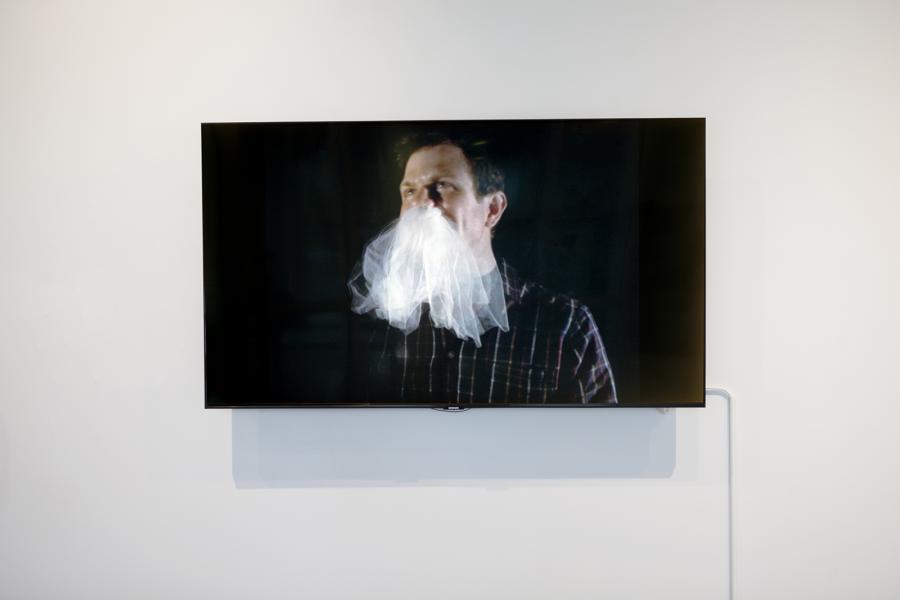 Video still of a man with ectoplasm-like fabric emerging from his mouth.