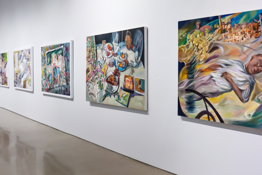 Gallery wall with five of Xianghui Guan’s narrative paintings in a row, each rich in color and surreal detail, combining domestic imagery, symbolic objects, and expressive figures.