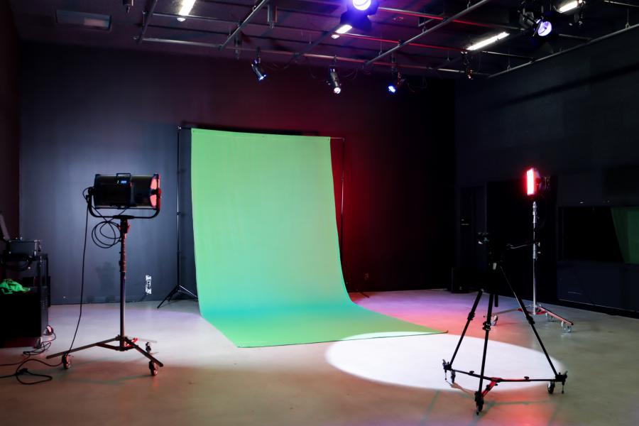 A green screen setup in the School of Art Sound Stage, with studio lights and a camera tripod arranged for video production.