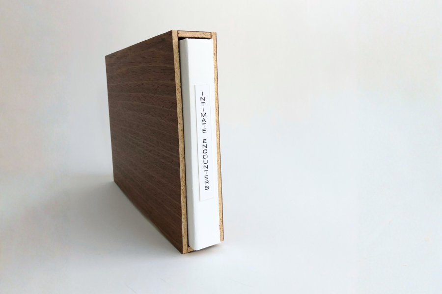 Angled view of Intimate Encounters in a wooden slipcase on a white background, showing the white spine label reading “INTIMATE ENCOUNTERS.”