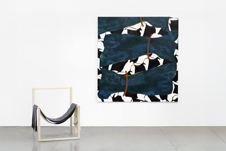 Gallery view showing freestanding wooden supports holding painted textile panels, with framed paintings visible along the walls.