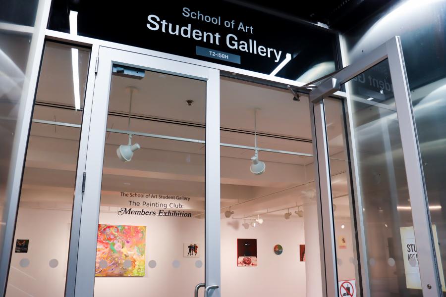 Entrance to the University of Manitoba School of Art Student Gallery, with exhibition signage visible through open glass doors.