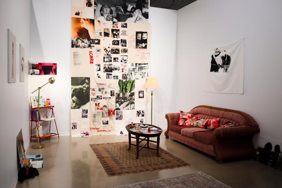 Interactive installation featuring books, photographs, and archival materials on a coffee table.