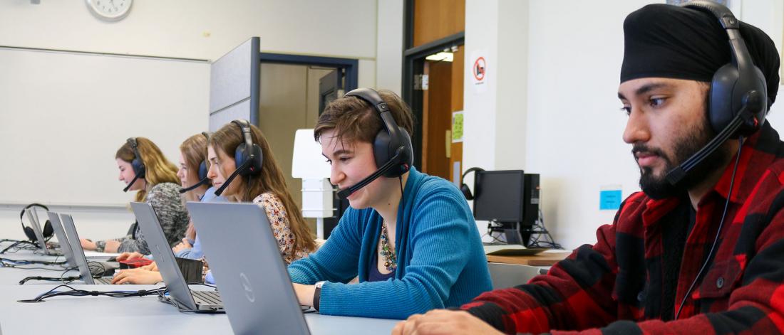 Students work at laptops in the Language Centre lab with headsets on.