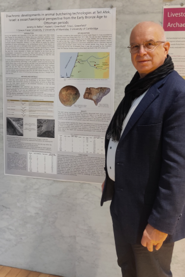 Man with scarf and blazer standing in front of a research poster.