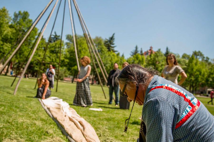 A group of people work together to make a Tee Pee.
