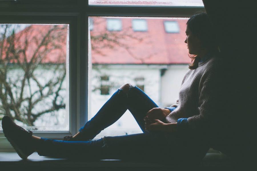 A person is seated at a window looking outside.