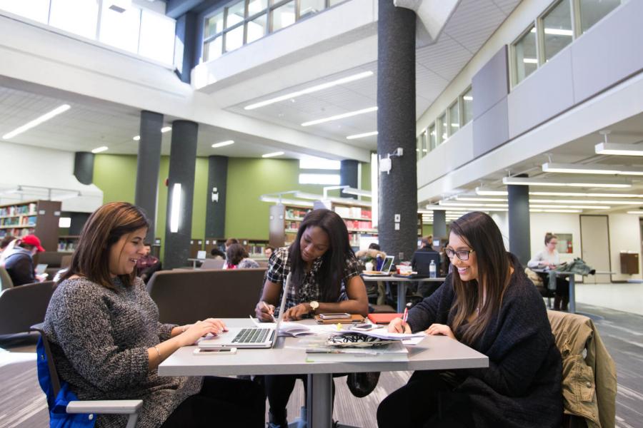 Three students studying together in a library. 