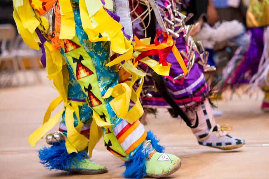 Partipants of the annual traditional graduation pow wow dance in traditional clothing.