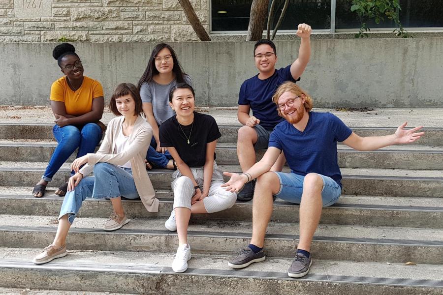 Group of Arts Ambassadors sitting on stairs outdoors together.