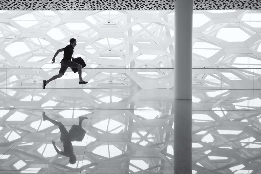 Silhouette of man running with a briefcase in his hand.