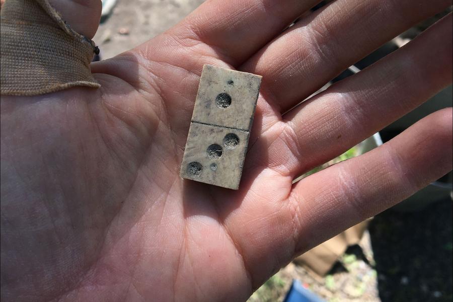 Old domino tile bring held in a hand.