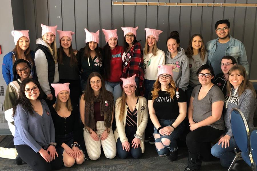 Group of high school students, many wearing a matching pink toque.