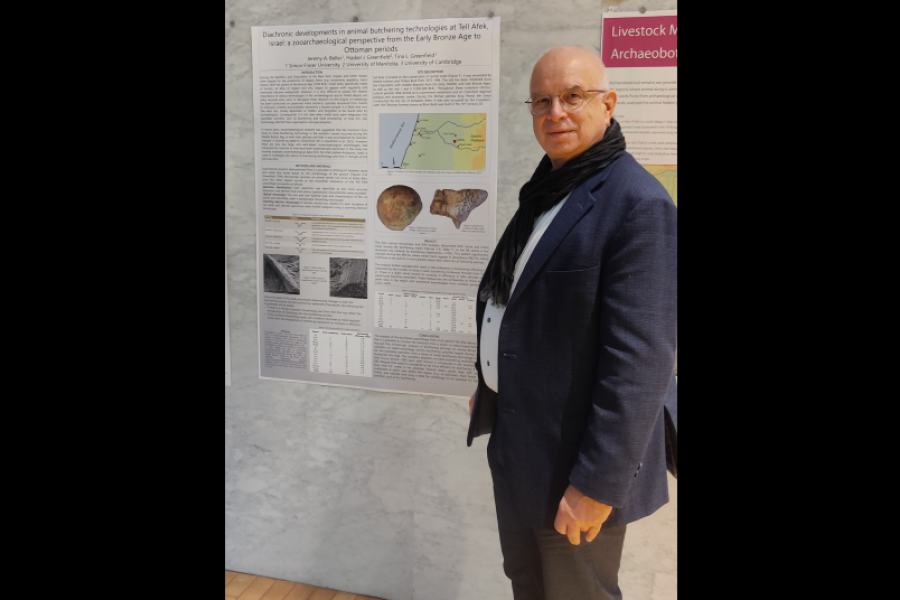 Man with scarf and blazer standing in front of a research poster.