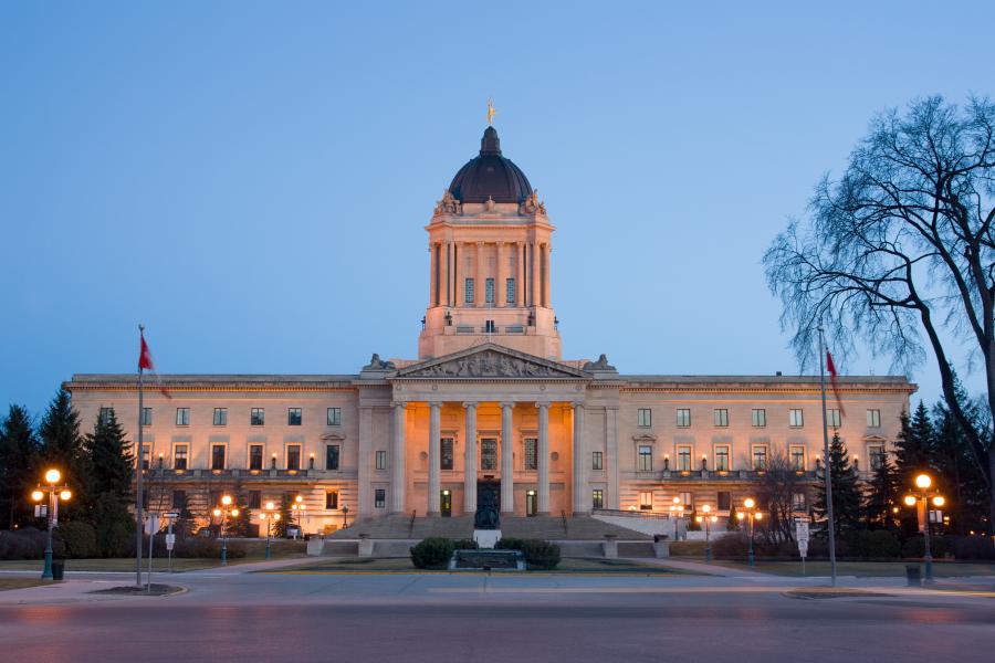 Manitoba legislature building lit up in front of an evening sky.