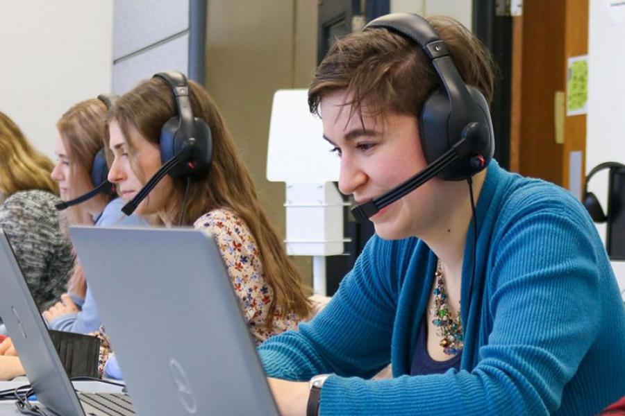 Row of students wearing headphones, looking at laptops in the Language Centre.