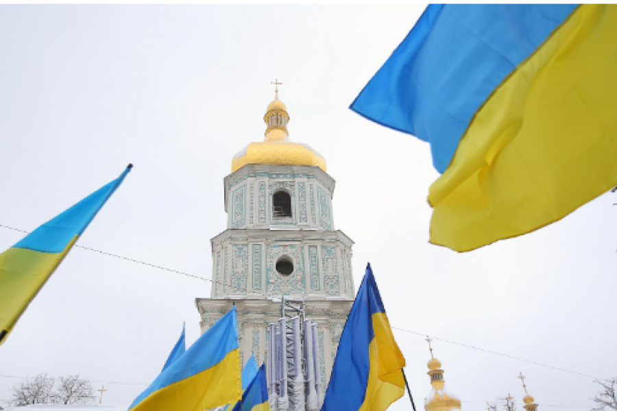 Ukraine flags in front of a church steeple.