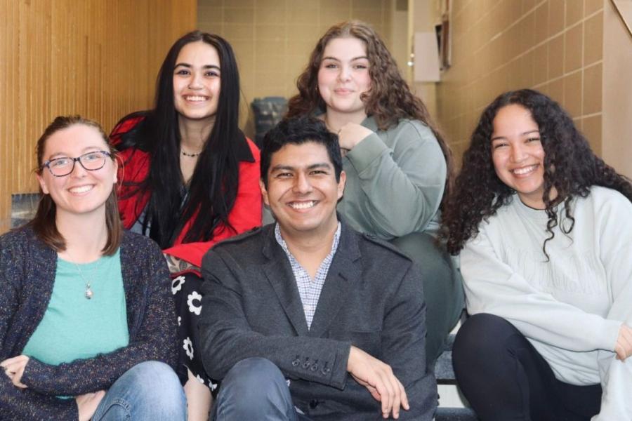 Group of five students sitting on stairs. 