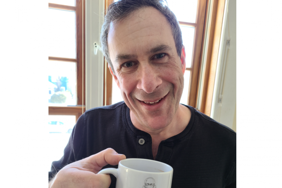 A profile photo of Mike Libin holding a coffee in front of a sunny window.