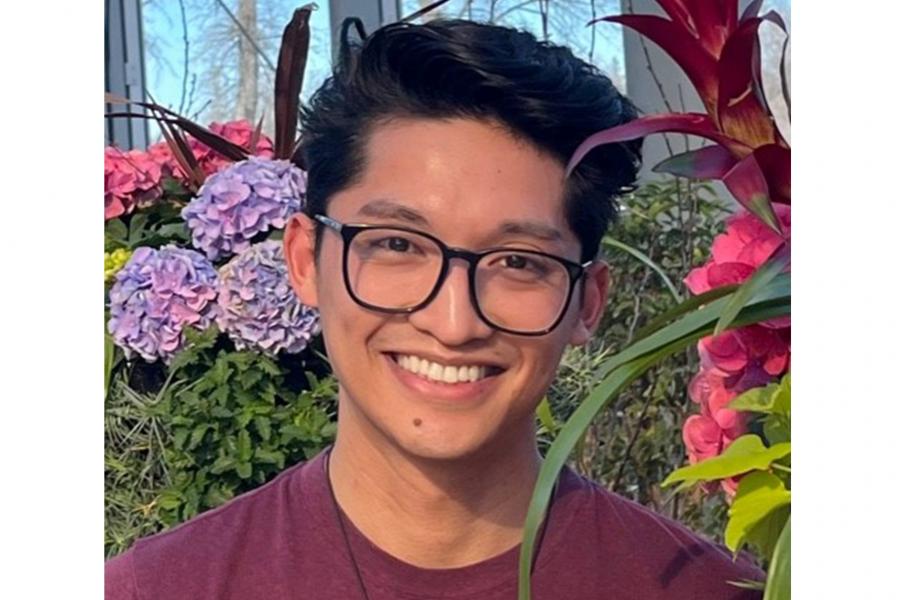Headshot of Ahrben Tumambing wearing glasses and in front of a background of flowers.