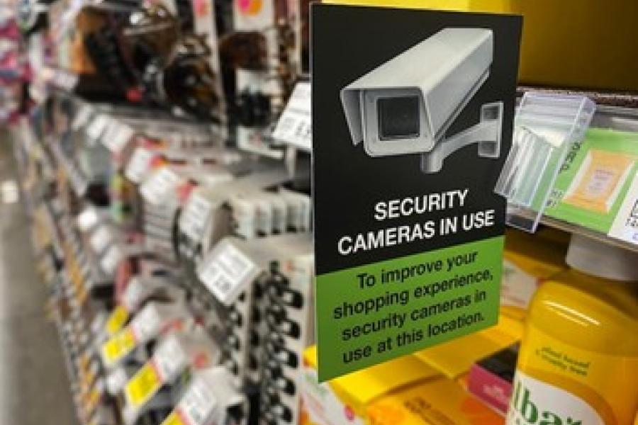 Sign in a retail store aisle that says, Security cameras in use. 