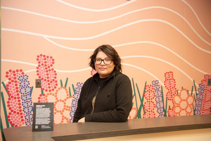 Artist Carly Morrisseau in front of their mural.