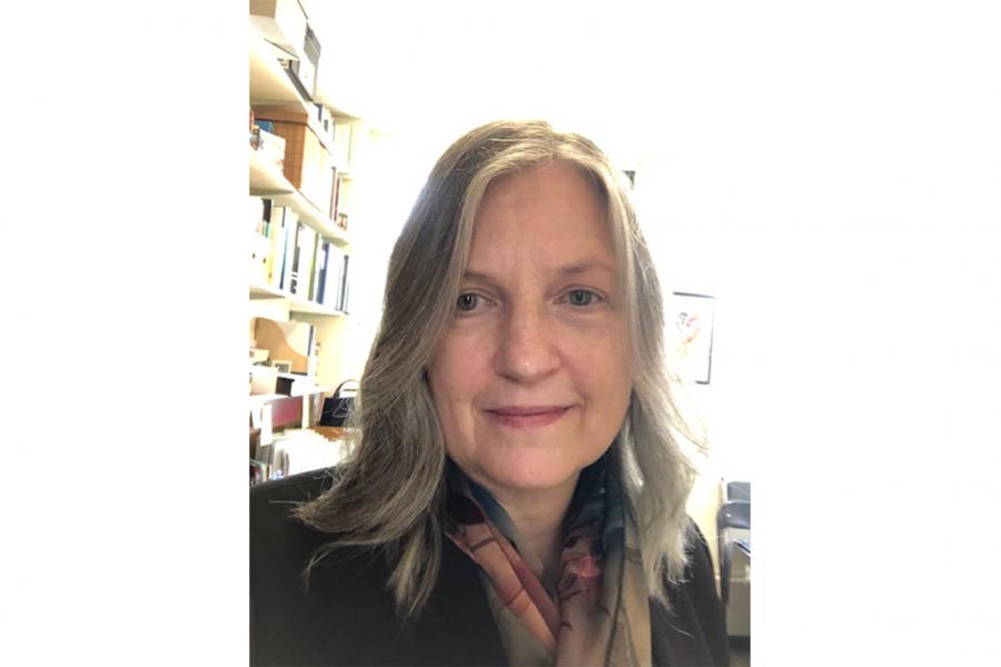 A headshot of Katrina Dunn in her office with books in shelve at the background