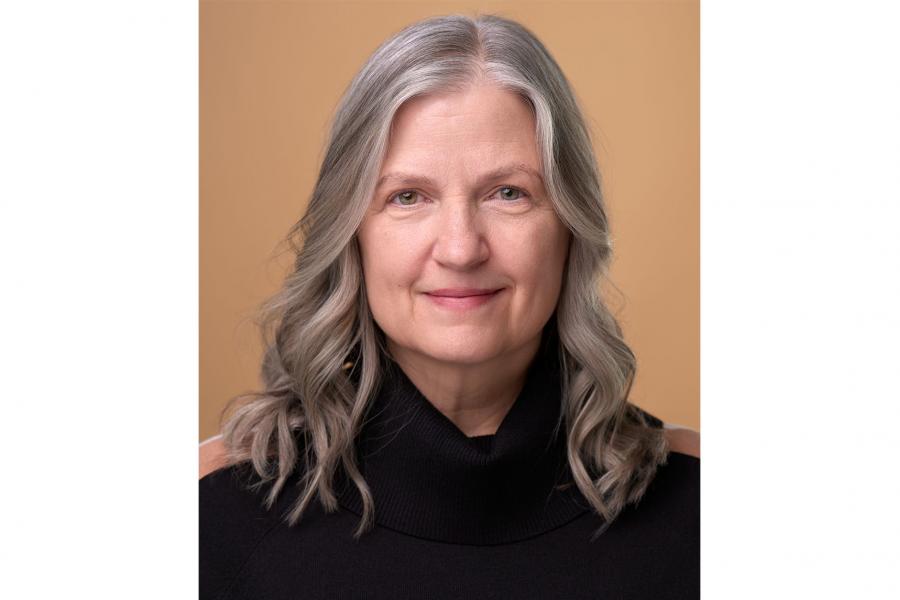 A headshot of Katrina Dunn in front of a brown background