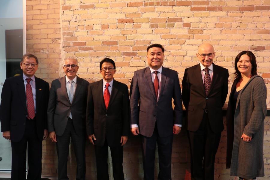 Group of six people standing in front of a brick wall. 