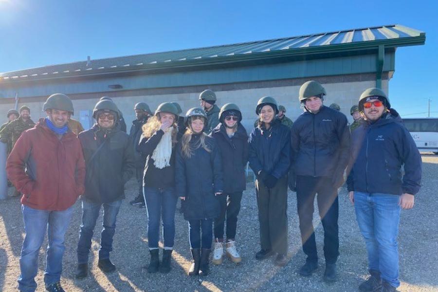 Group of eight students standing in a row, all wearing military helmets.