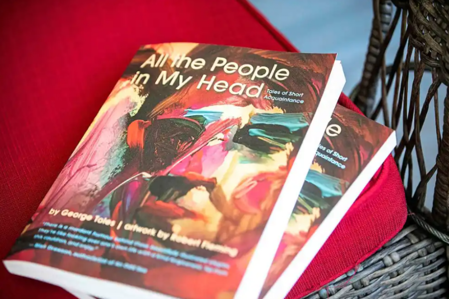 A stack of the book "All the People in My Head" sitting on an outdoor patio chair. 