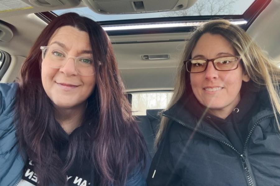 Two people taking a selfie inside the front seat of a car.