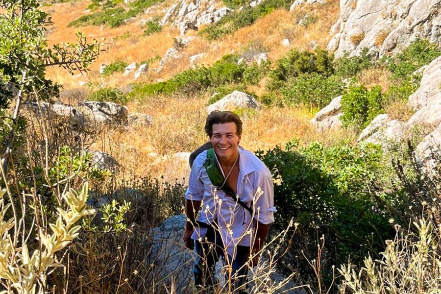 Man standing in a valley with mountains surrounding him.