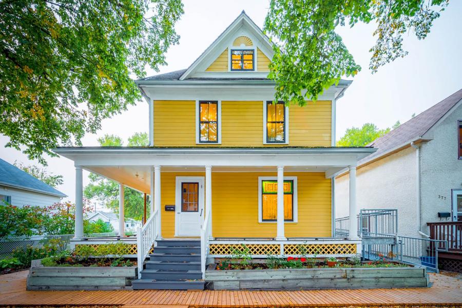 A brightly painted yellow house seen from the curb.