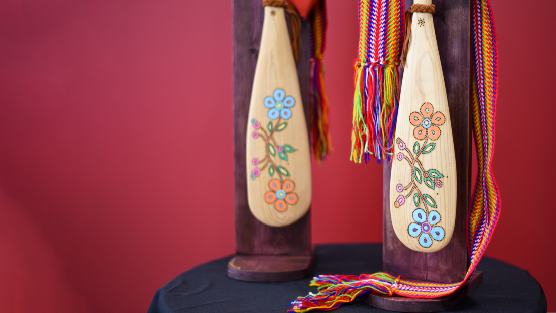 Two wood paddles on a table with a black table top. The paddles have floral designs on the end. At the Asper School of Business. 