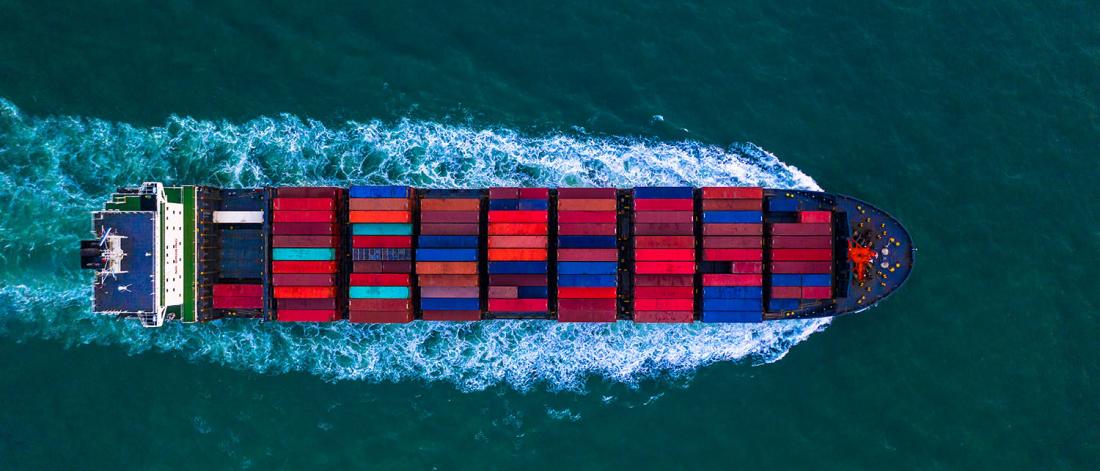 Birds eye view of a ship carrying colourful red, blue, and teal shipping containers.